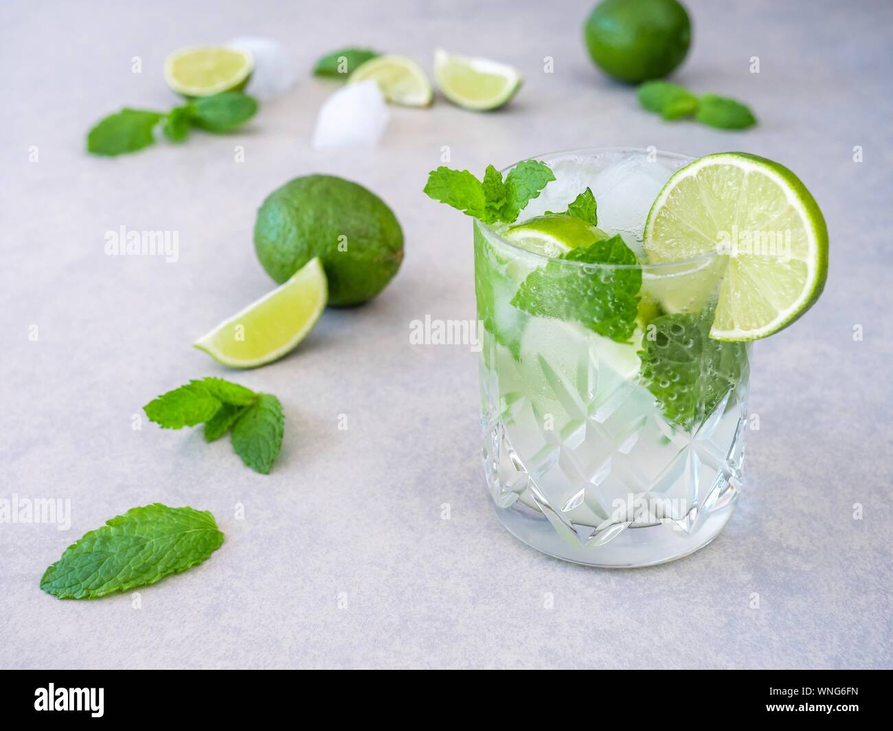 Un cocktail mojito realizzato da menta fresca e lime in un taglio di un bicchiere di vetro contro uno sfondo chiaro Foto Stock