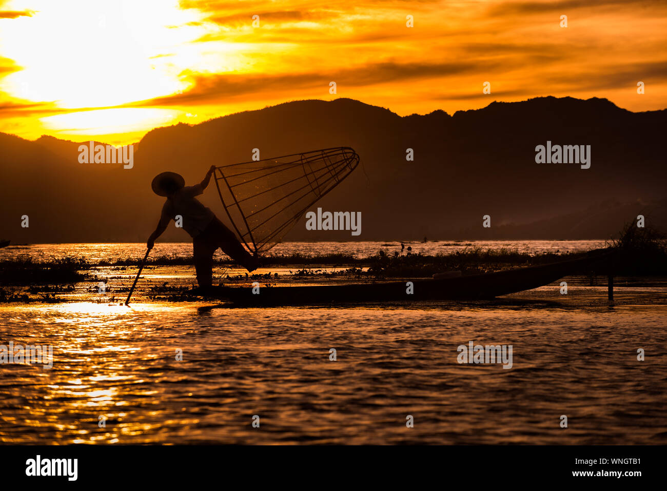 Pescatore Intha posa con rete conica al tramonto, Lago Inle nel Nyaungshwe Township parte delle colline Shan in MYANMAR Birmania Foto Stock