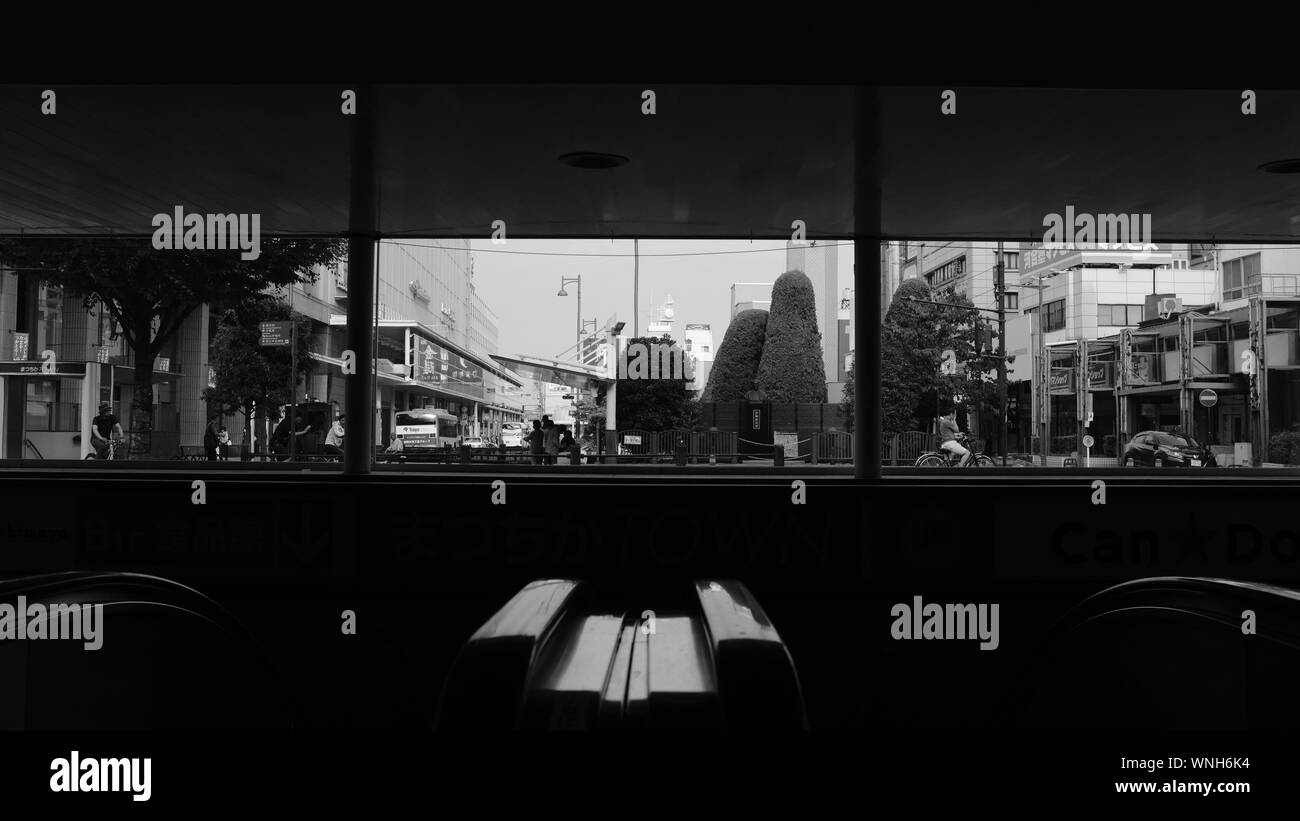 Vista in scala di grigi di una città con edifici, alberi e trasporto dall'interno di un bar Foto Stock