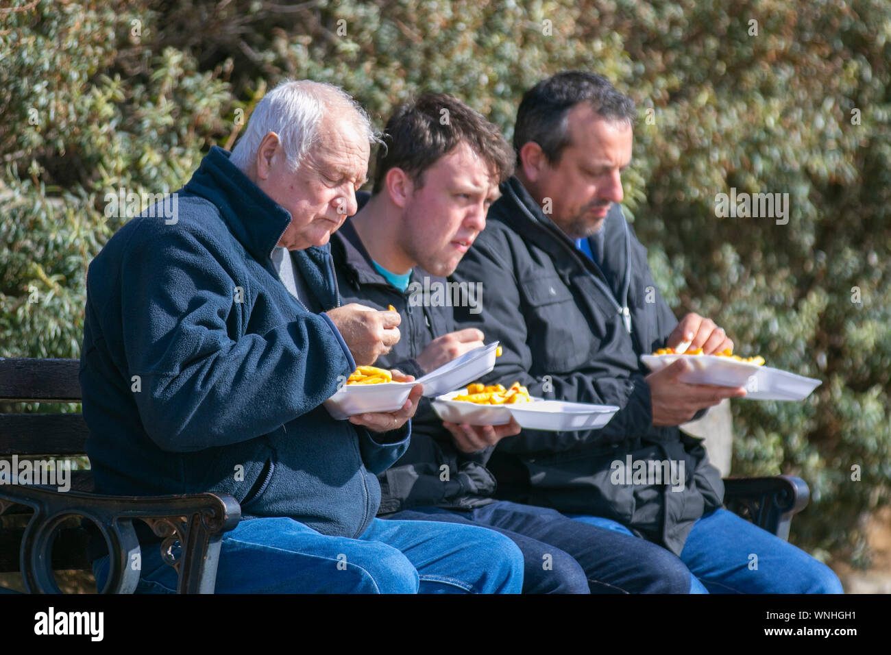 Tre uomini di mangiare pesce e cena di chip a Lytham St Annes, Regno Unito Foto Stock