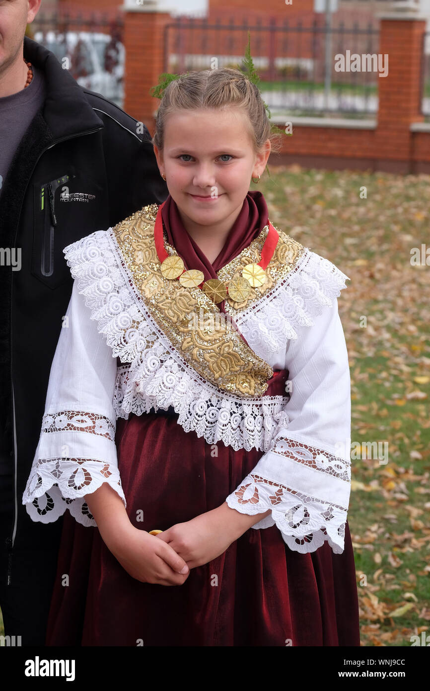 Ragazza vestita in costumi folcloristici andare in chiesa durante la Santa Messa il giorno del Ringraziamento in Stitar, Croazia Foto Stock