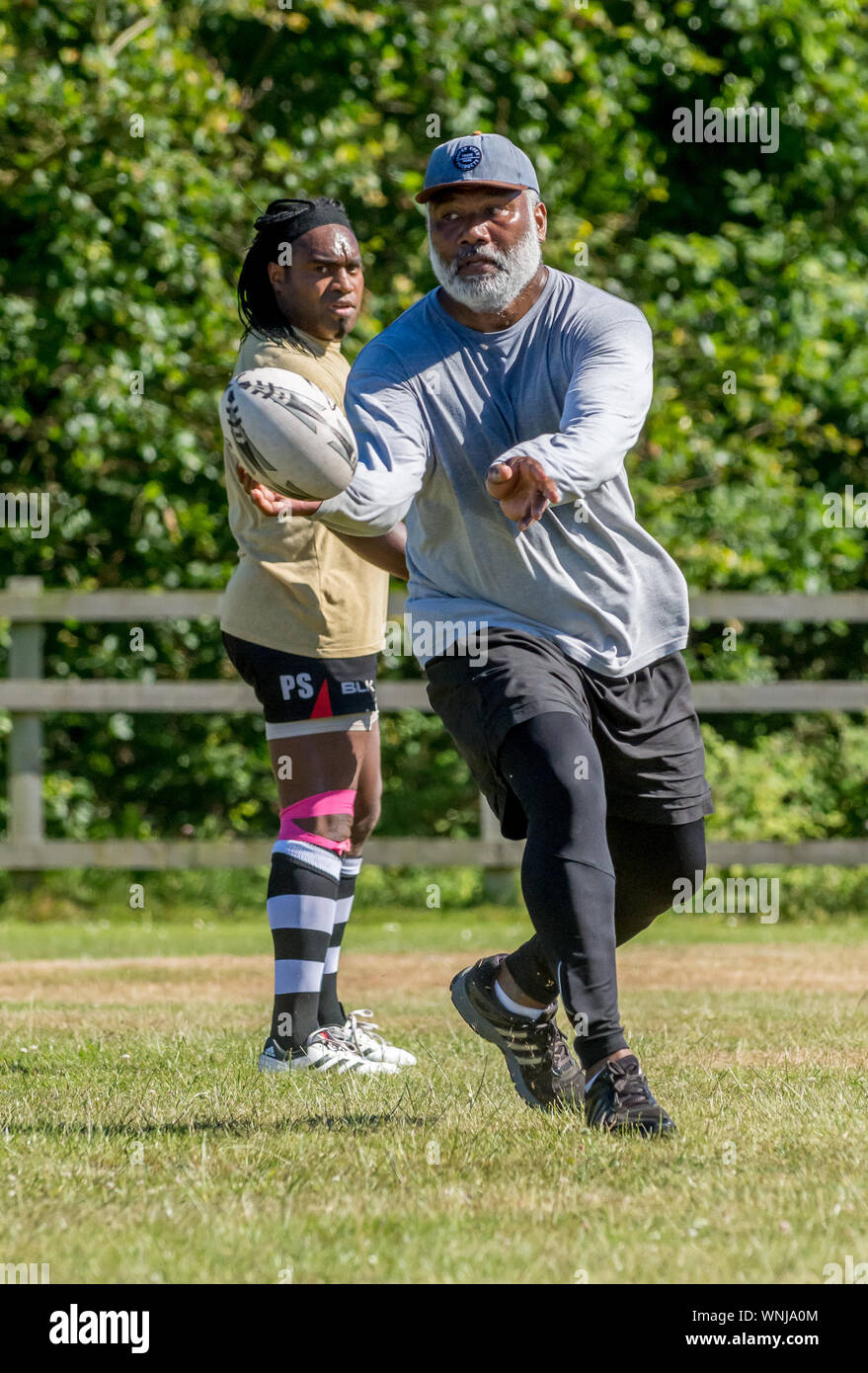 Amateur rugby touch player (maschio, 40-50 y) genera un pass di rugby con la palla in aria a metà strada per il compagno di squadra fuori tiro Foto Stock