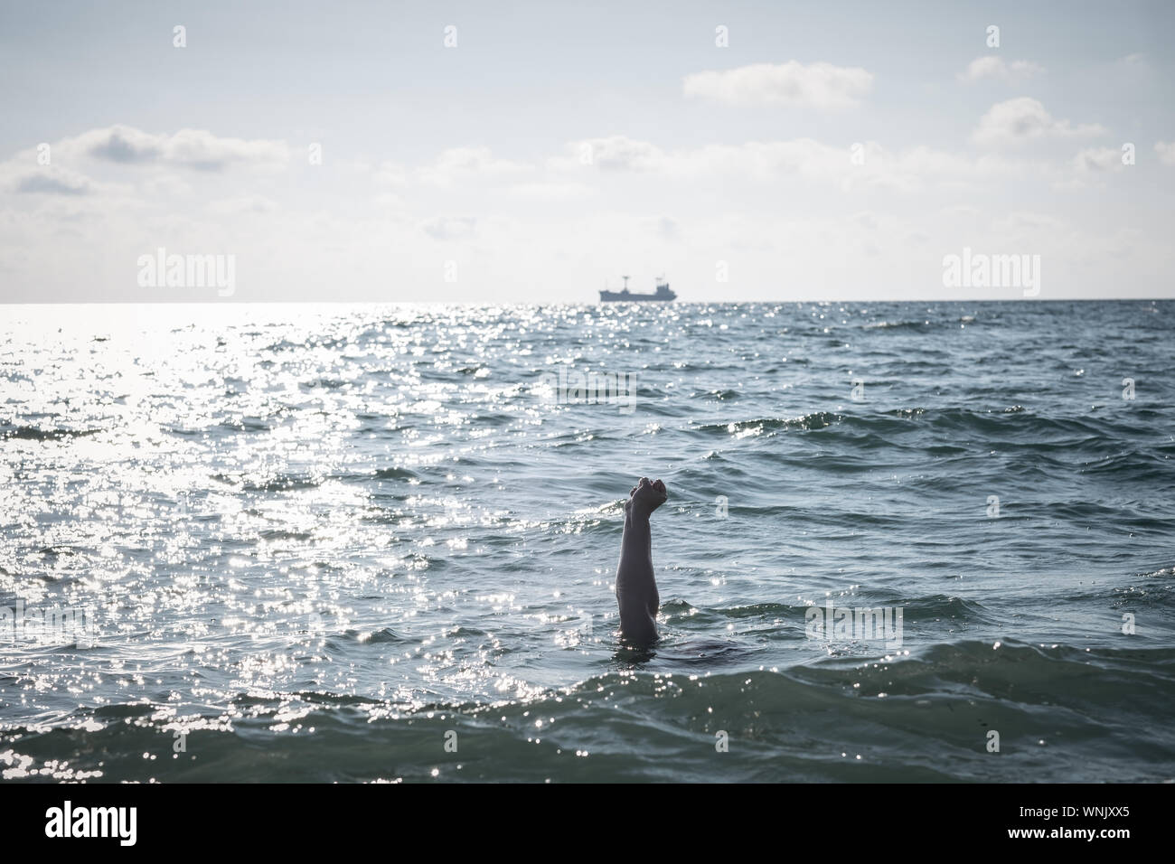 Unica mano di annegamento di uomo in mare per chiedere aiuto. sticking fuori dall'acqua Foto Stock