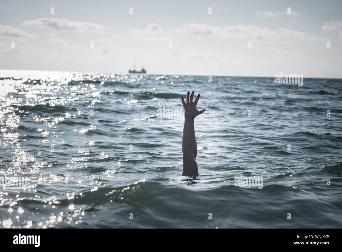 Unica mano di annegamento di uomo in mare per chiedere aiuto. sticking fuori dall'acqua Foto Stock