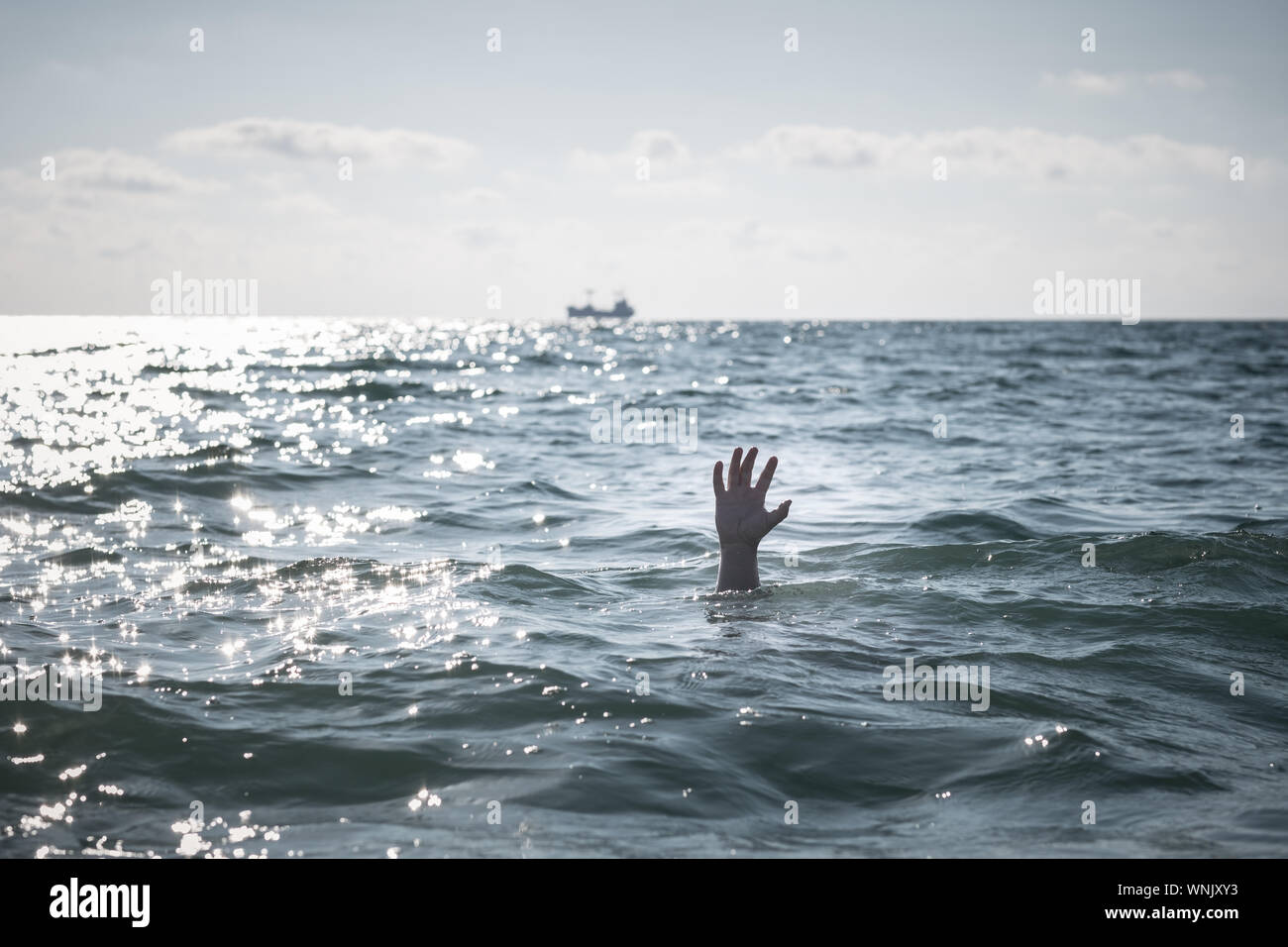Unica mano di annegamento di uomo in mare per chiedere aiuto. sticking fuori dall'acqua Foto Stock