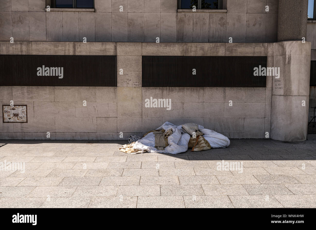 Un mucchio di coperte appartenenti ad una persona senza dimora al di sotto di un calcestruzzo blocco ufficio, central Madrid Spagna Foto Stock