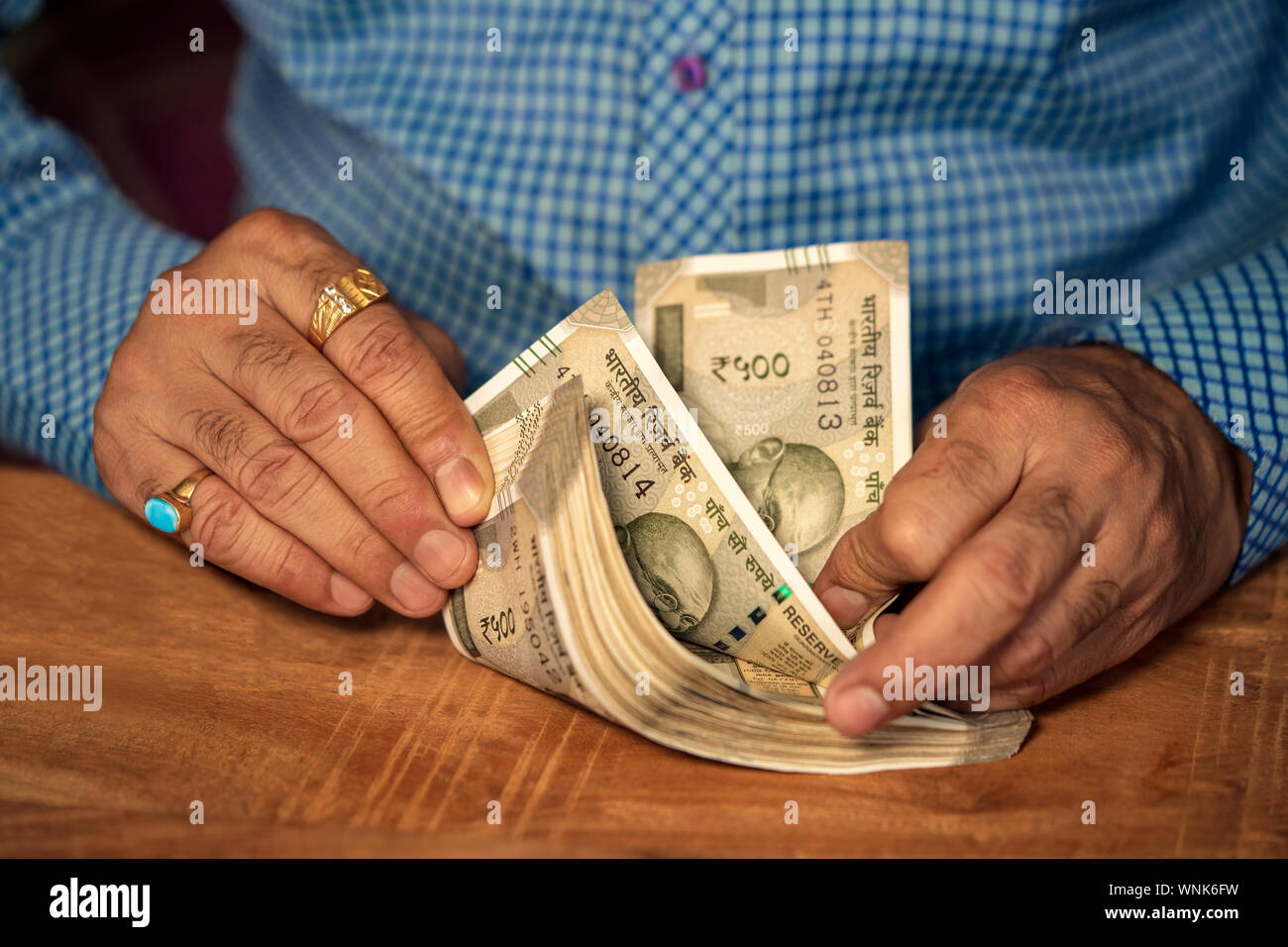 Commerciante indiano il conteggio di un lotto di cinque cento rupee note su un tavolo di legno. Concetto di denaro contando, stipendio, il versamento dei fondi e dello sfondo. Foto Stock