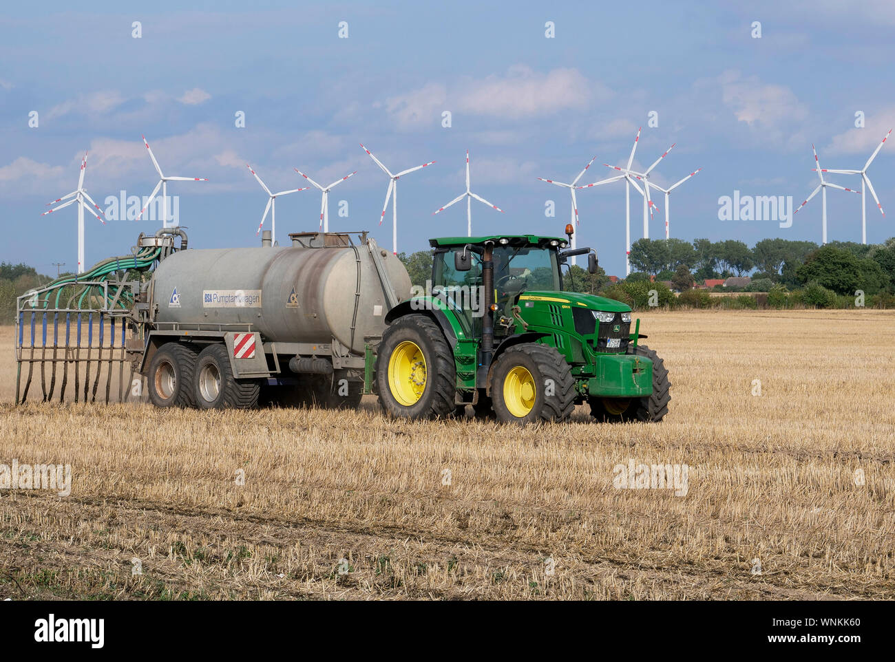 GERMANIA, agricoltura, trattore John Deere di grandi dimensioni con carro cisterna per liquame su campo, concime liquido spruzzato su campo raccolto, liquame da capannoni di maiale e vacca con ad alto contenuto di nitrati inquinamenti acque sotterranee / DEUTSCHLAND, Mecklenburg Vorpommern, Traktor mit Guellewagen bringt Guelle auf ein Stoppelfeld aus, Zu viele nitrato belasten das Grundwasser Foto Stock