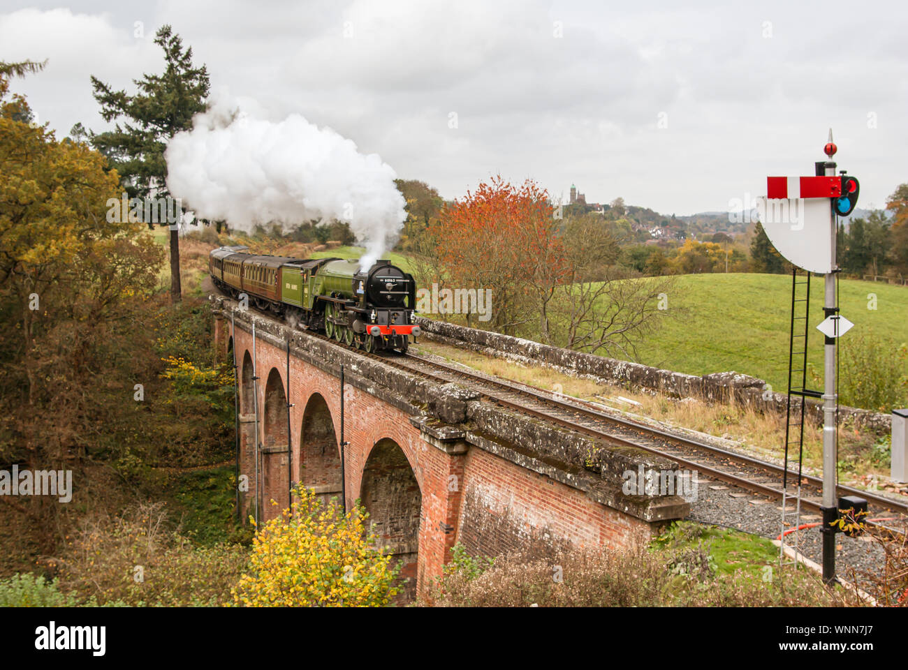 Il treno a vapore 'Tornado' restaurato con carrozze che attraversano un ponte verso un segnale con pennacchio di fumo Foto Stock