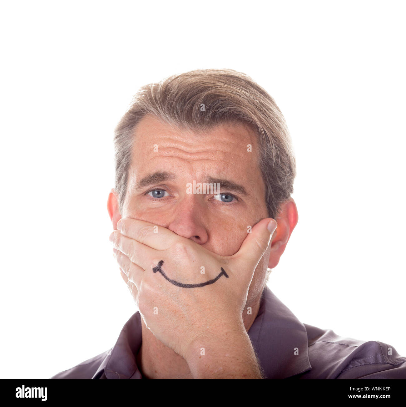 L'uomo nascondendo il suo vero emozioni coprendo la sua bocca con un sorriso disegnato sulla sua mano. Foto Stock