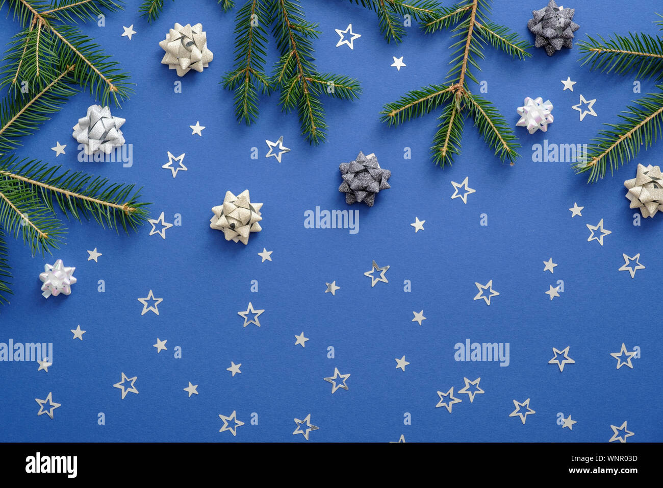 Natale o Capodanno composizione fatta di albero di Natale Abete rami, coriandoli di fiocchi di neve su sfondo blu. Natale o Capodanno concetto. Lay piatto Foto Stock