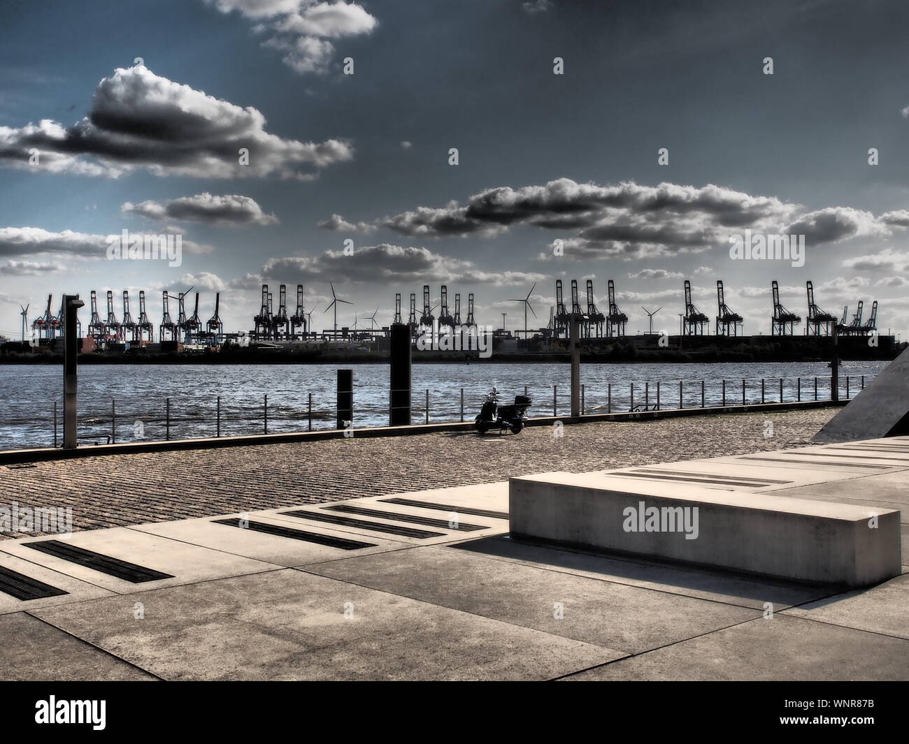 L'area del porto di Amburgo lungo il fiume con le gru e gli edifici in tono drammatico Foto Stock
