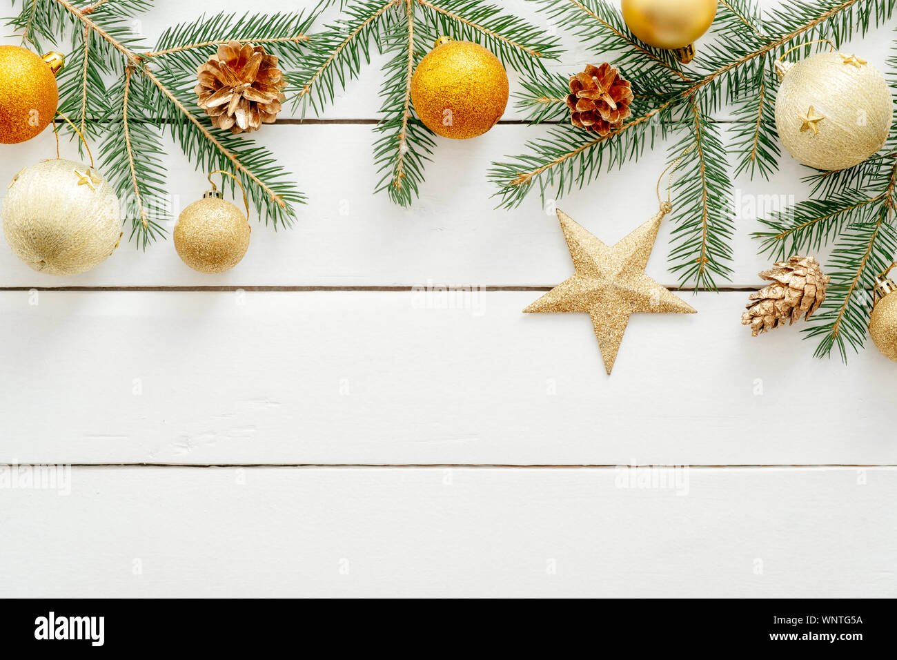 Scheda di Natale con decorazioni dorate, palline, stella, Abete rami, pigne di legno su sfondo bianco. Piatto di Natale laici con decorazioni moderne. A Foto Stock
