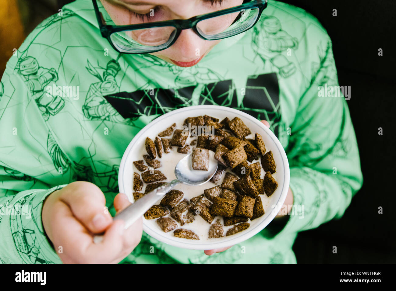 Ragazzo mangiando cioccolato cereali da una ciotola di bianco. Foto Stock