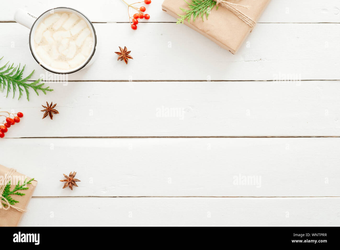 Composizione di natale. Lay piatto tazza di cioccolata calda con marshmallow, Abete rami, bacca rossa, presenta sul legno tavolo bianco. Natale, inverno Foto Stock