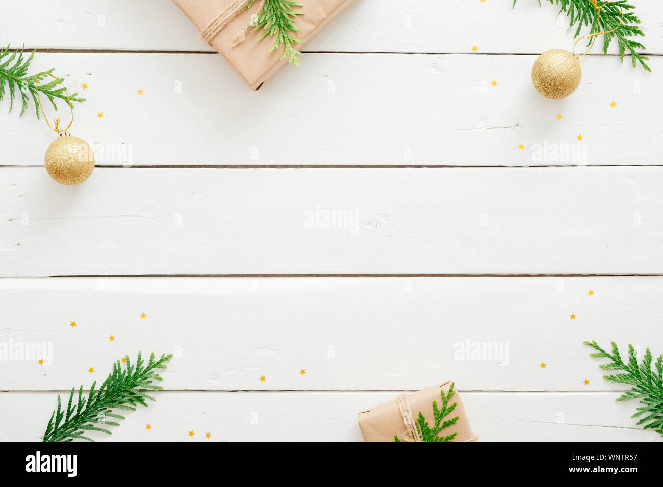 Natale composizione minima. Telaio di Natale fatto di Abete rami, decorazioni dorate, regali avvolti su bianco scrivania in legno. Natale, inverno, n Foto Stock
