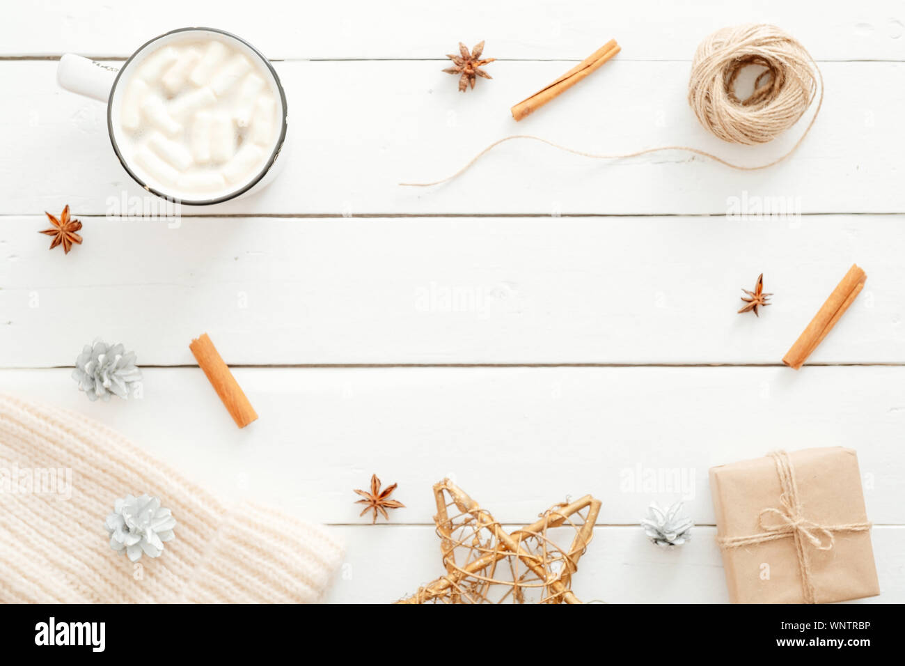 Natale composizione minima. Flatlay tazza di cioccolata calda con marshmallow, bastoncini di cannella, decorazioni di Natale, confezione regalo avvolto in carta kraft, lavorati a maglia Foto Stock