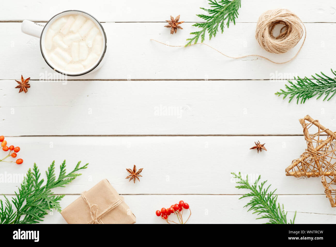 Composizione di natale. Cornice in abete rami, decorazioni di Natale, tazza di cioccolata calda con marshmallow, bacca rossa di legno su sfondo bianco. Foto Stock