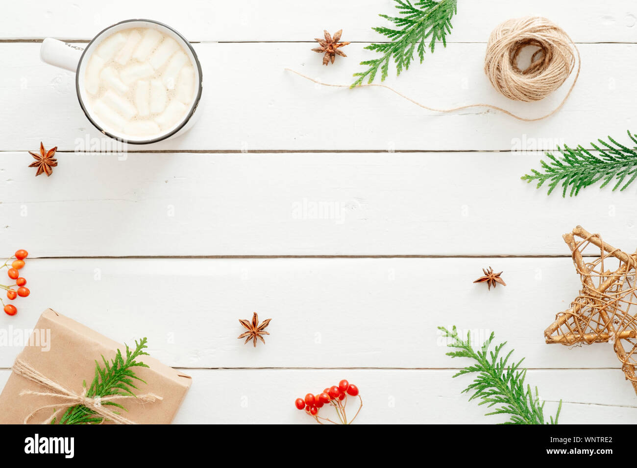 Composizione di natale. Cornice in abete rami, decorazione, tazza di cioccolata calda con marshmallow, bacca rossa di legno su sfondo bianco. Appartamento Foto Stock
