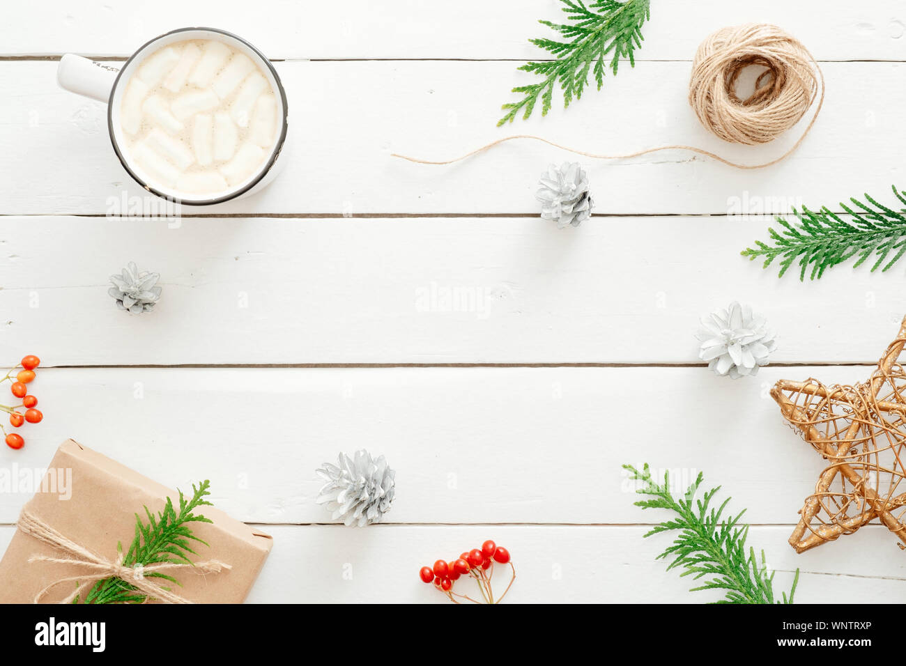 Natale flatlay composizione. Cioccolata calda con marshmallows cup, Abete rami, confezione regalo di natale decorazione in legno rustico backgroun bianco Foto Stock