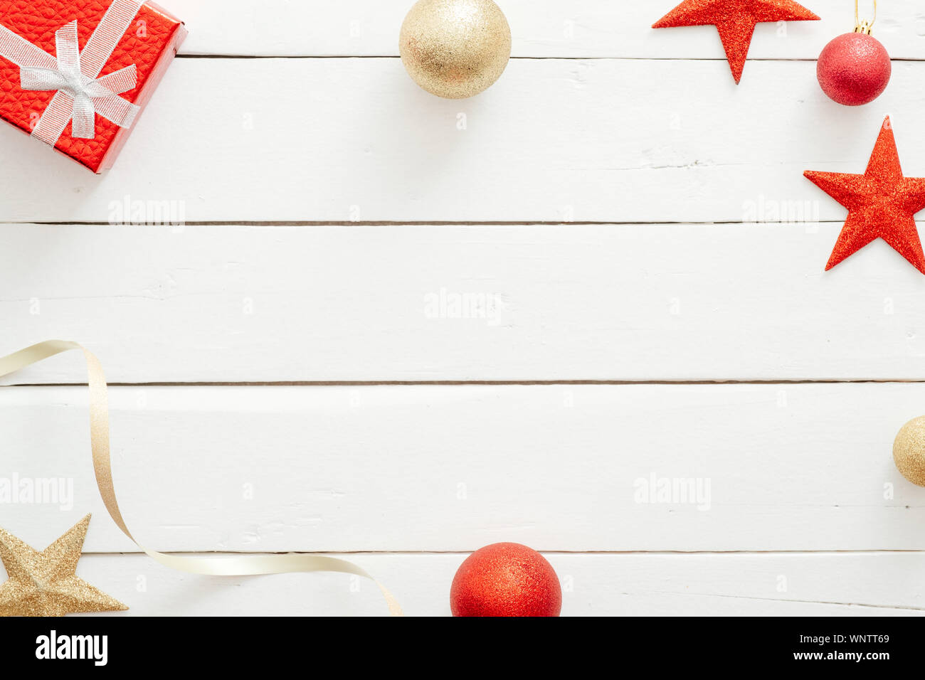 Composizione di natale. Telaio di Natale realizzata in confezione regalo rossa, stelle, palline dorate, ornamenti in legno su sfondo bianco. Biglietto di auguri Modello, inverno Foto Stock
