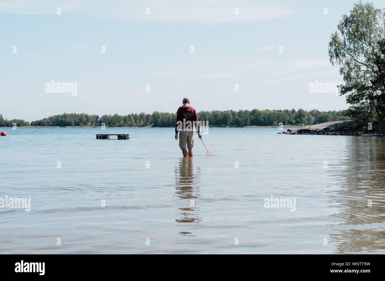Uomo in piedi in acqua con una rete da pesca in estate Foto Stock