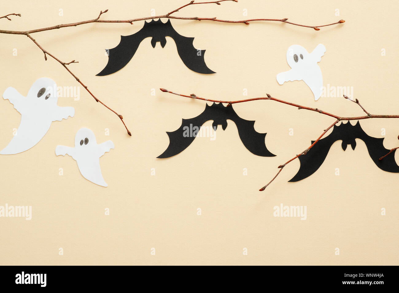 Carta di Halloween Decorazioni pastello su sfondo beige. Pipistrelli di nero e bianco fantasmi seduti sul ramo. Concetto di Halloween. Appartamento laico, vista dall'alto, copia spa Foto Stock