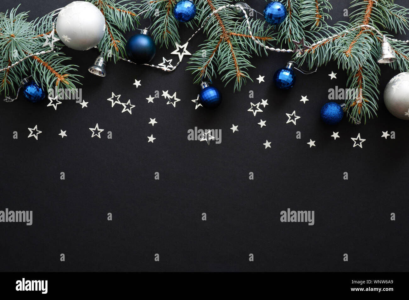 Composizione di natale con il blu e il nastro delle decorazioni moderne, baubles, Abete rami scuri su sfondo nero. Elegante banner di Natale mockup, g Foto Stock
