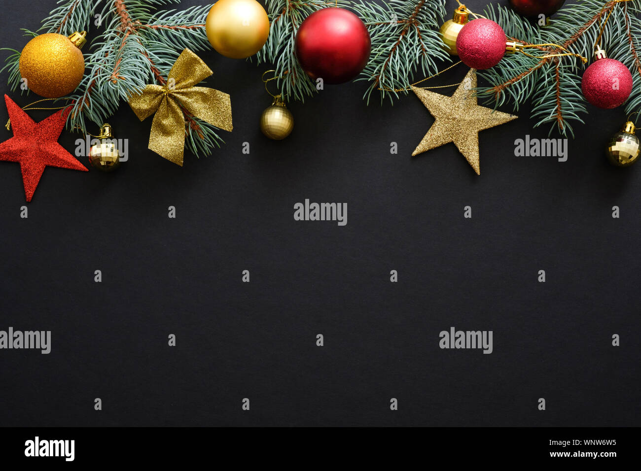 Vacanze di Natale composizione. Rosso e oro decorazioni di Natale, baubles, Abete rami scuri su sfondo nero con copia spazio. Banner mocku Foto Stock