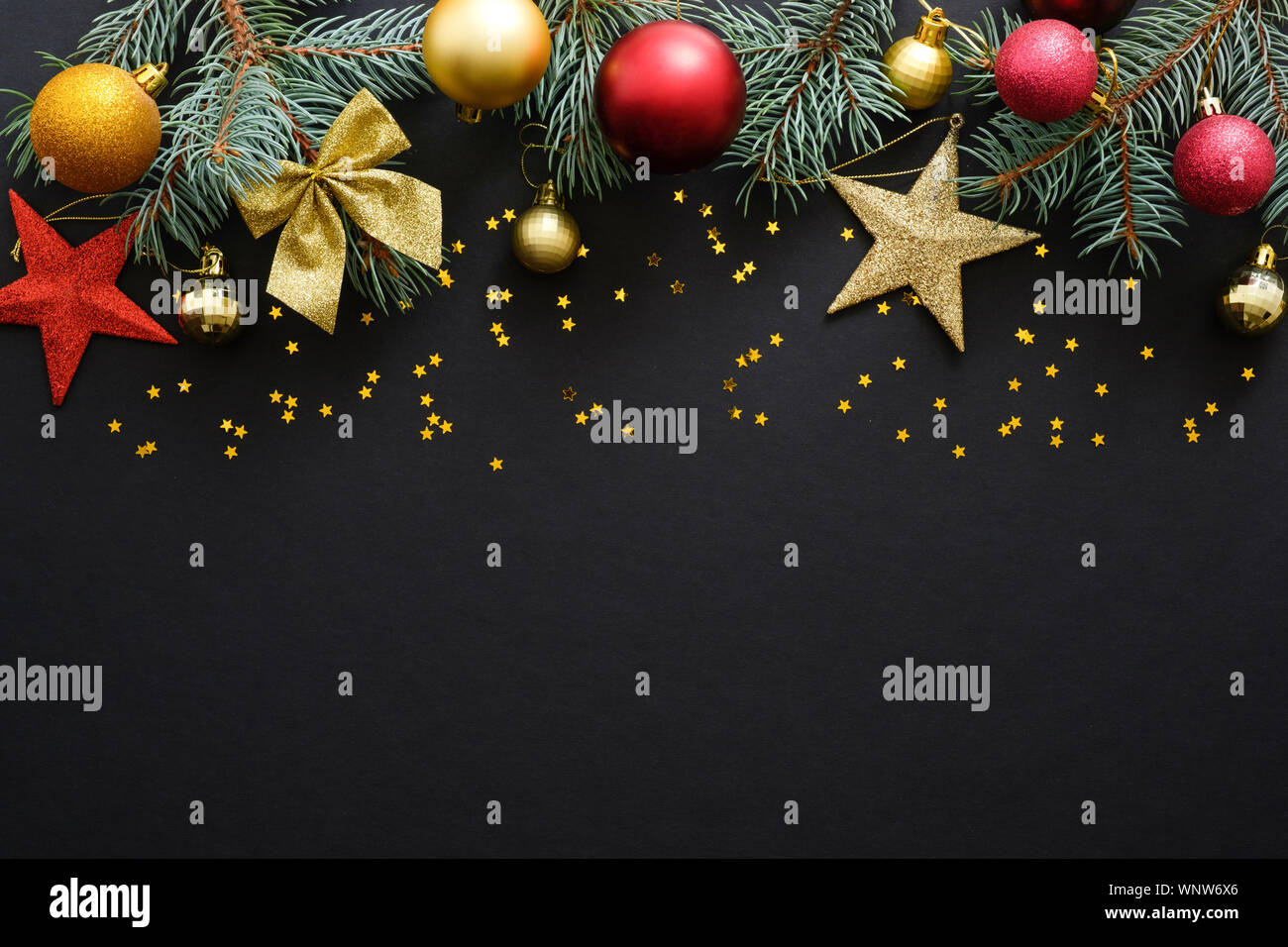 Vacanze di Natale composizione. Festa di Natale decorazioni, baubles, Abete rami, coriandoli star scuro su sfondo nero con copia spazio. Bann Foto Stock