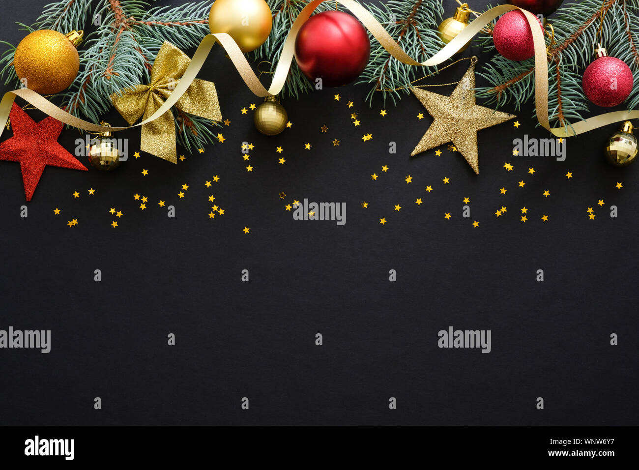 Vacanze di Natale composizione. Festa di Natale decorazioni, baubles, Abete rami, coriandoli star scuro su sfondo nero con copia spazio. Bann Foto Stock