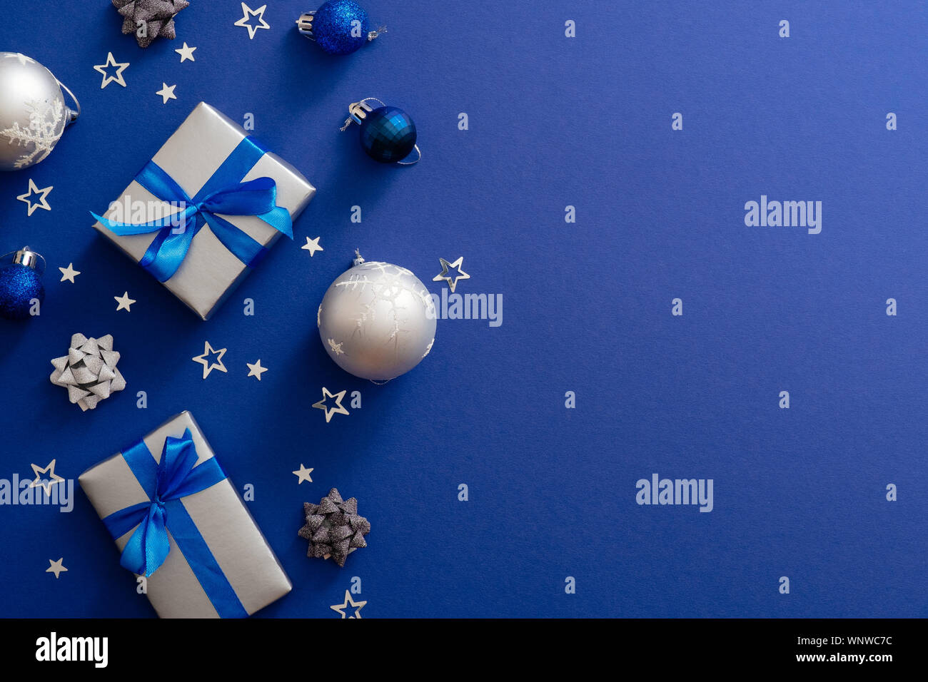 Natale argento regalo scatole o presenta con nastro di prua, baubles, decorazioni, coriandoli sul magico sfondo blu scuro con copia spazio. Vintage Xmas gr Foto Stock