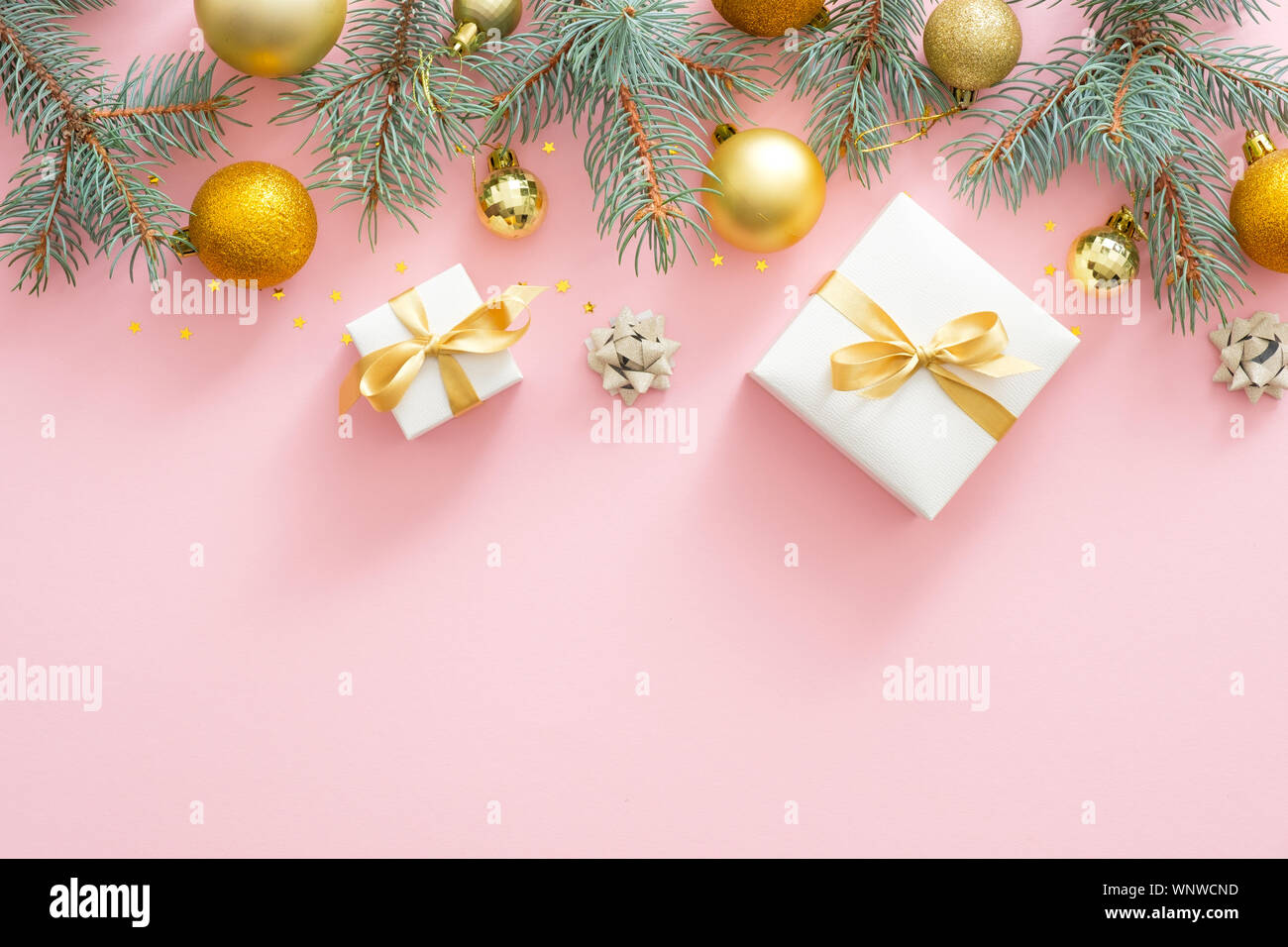 Telaio di Natale confine con abete rami, Natale palline dorate, presenta sul rosa pastello sfondo. Appartamento laico, vista dall'alto. Foto Stock