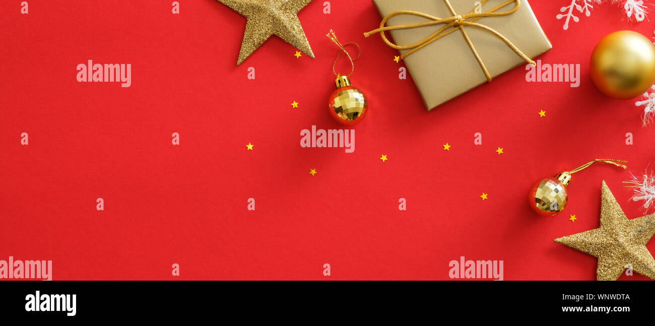 Banner di Natale mockup. Xmas decorazioni dorate su sfondo rosso. Lay piatto confezione regalo, stelle, sfere, scintillante di coriandoli. Orizzontale poster di Natale Foto Stock