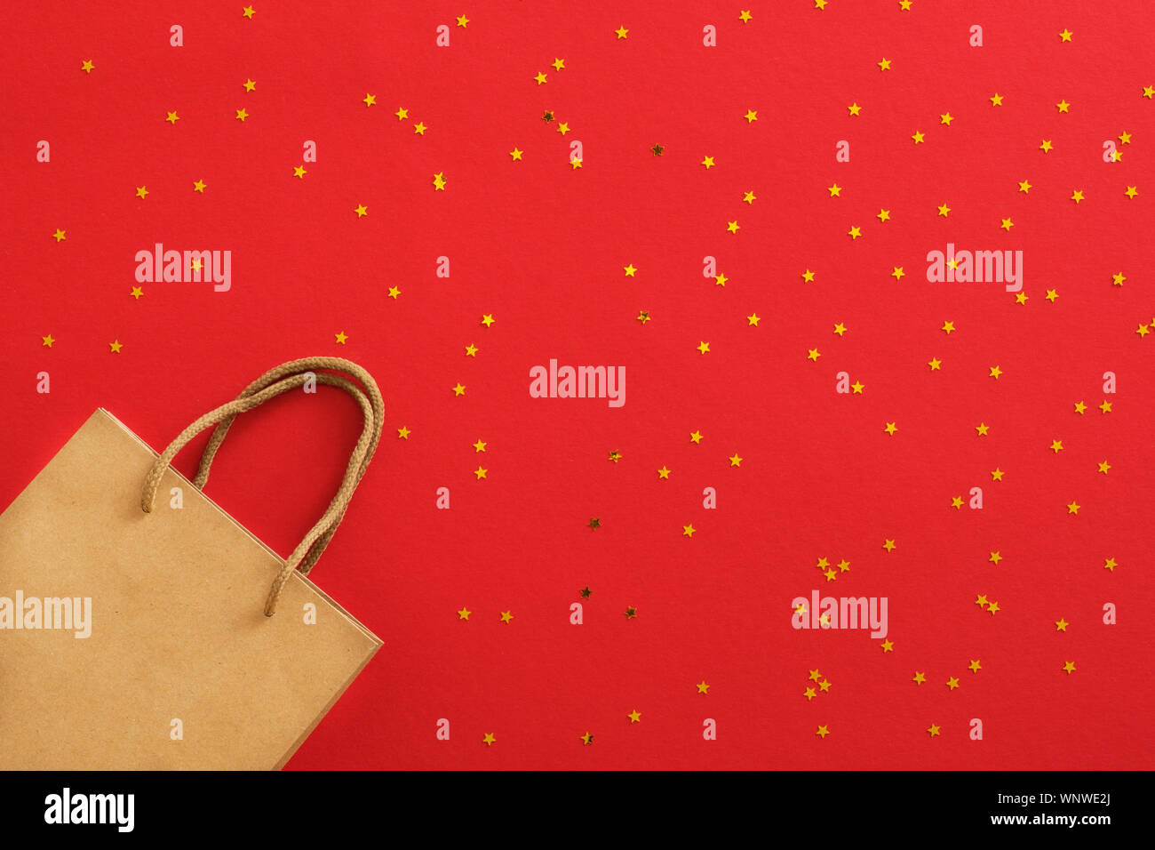 Banner di natale. Background design Natale di carta craft shopping bag e glitter golden coriandoli su sfondo rosso. Poster di natale, biglietto di auguri, h Foto Stock