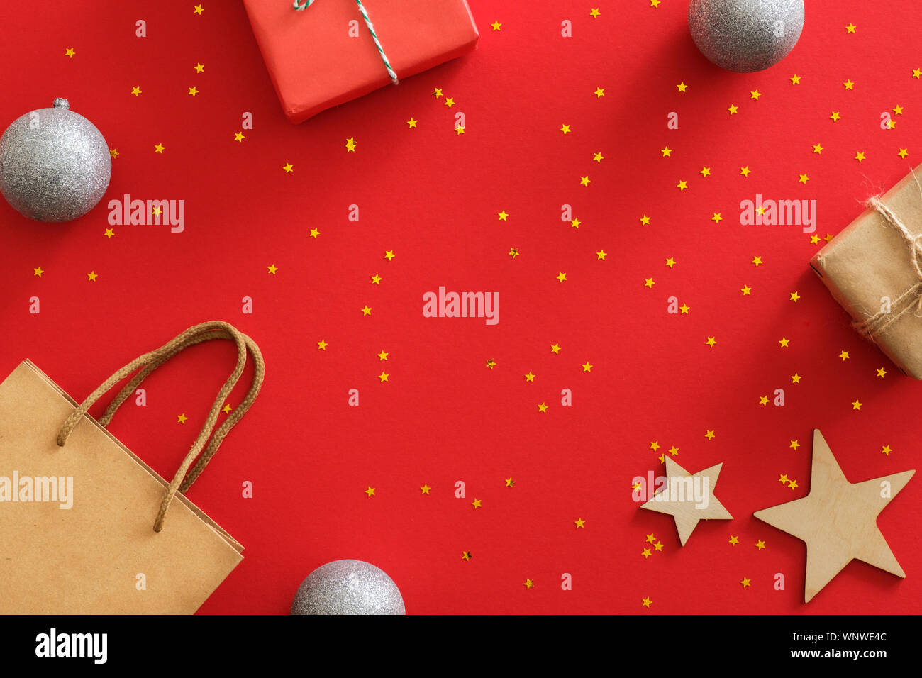 Anno nuovo Natale regali avvolti carta craft, fatti a mano in legno di stelle, decorazioni, glitter golden coriandoli su sfondo rosso. Xmas holiday celebrati Foto Stock