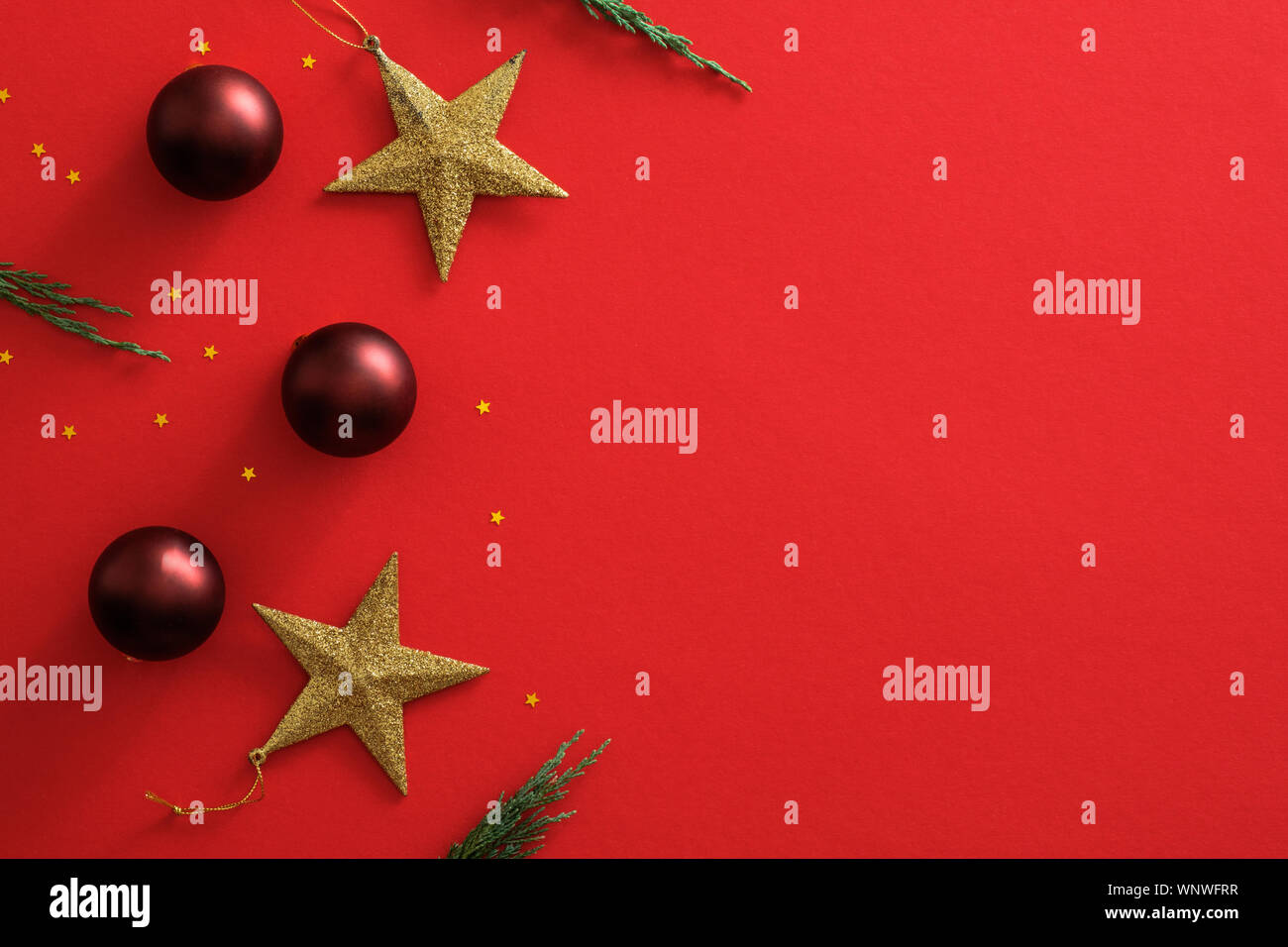 Addobbi natale decorazioni su sfondo rosso con copia spazio. Appartamento lay golden stars, rosso baubles sfere, scintillante di coriandoli. Poster di Natale moc Foto Stock