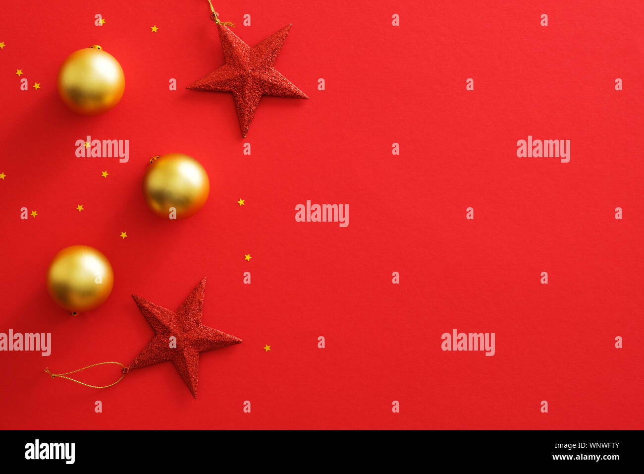 Addobbi natale decorazioni su sfondo rosso con copia spazio. Appartamento lay golden baubles sfere, stelle rosse, glitter coriandoli. Natale flyer mockup, Foto Stock