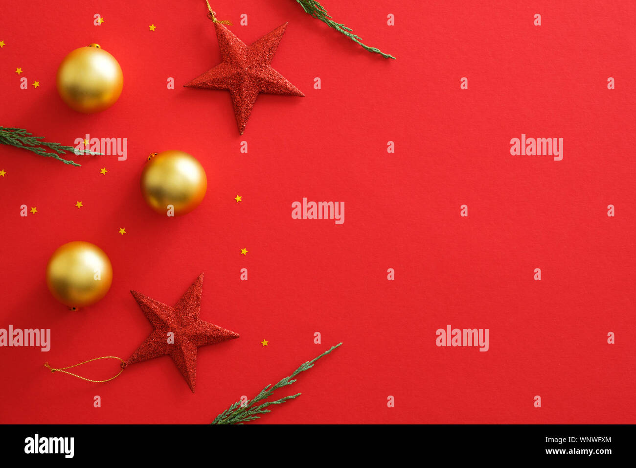 Addobbi natale decorazioni su sfondo rosso con copia spazio. Appartamento lay golden baubles sfere, stelle rosse, glitter coriandoli, Abete rami. Natale Foto Stock