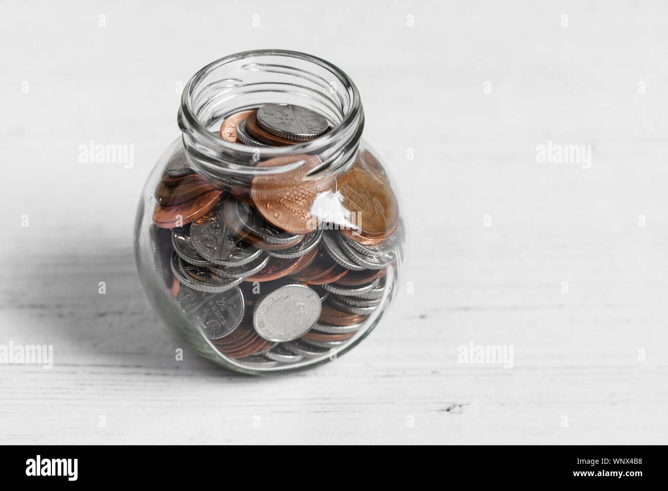 Coin jar su un tavolo bianco top, risparmi di denaro con il concetto di spazio di copia Foto Stock