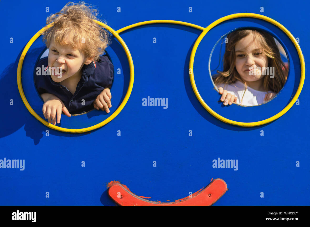 Un ragazzo e una ragazza loll presso il parco giochi. Due bambini rendendo grimace e divertirsi al parco giochi. Male Naughty kids concetto. Foto Stock