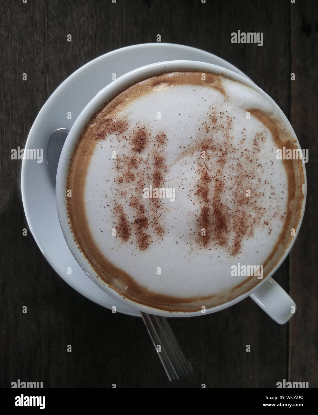 Chiusura del cappuccino o del latte con schiuma di schiumato in bianco con tazza di caffè nero sul tavolo di legno nel caffè cafe. Lo stile di vita del tempo di caffè , latte art concetto. Foto Stock