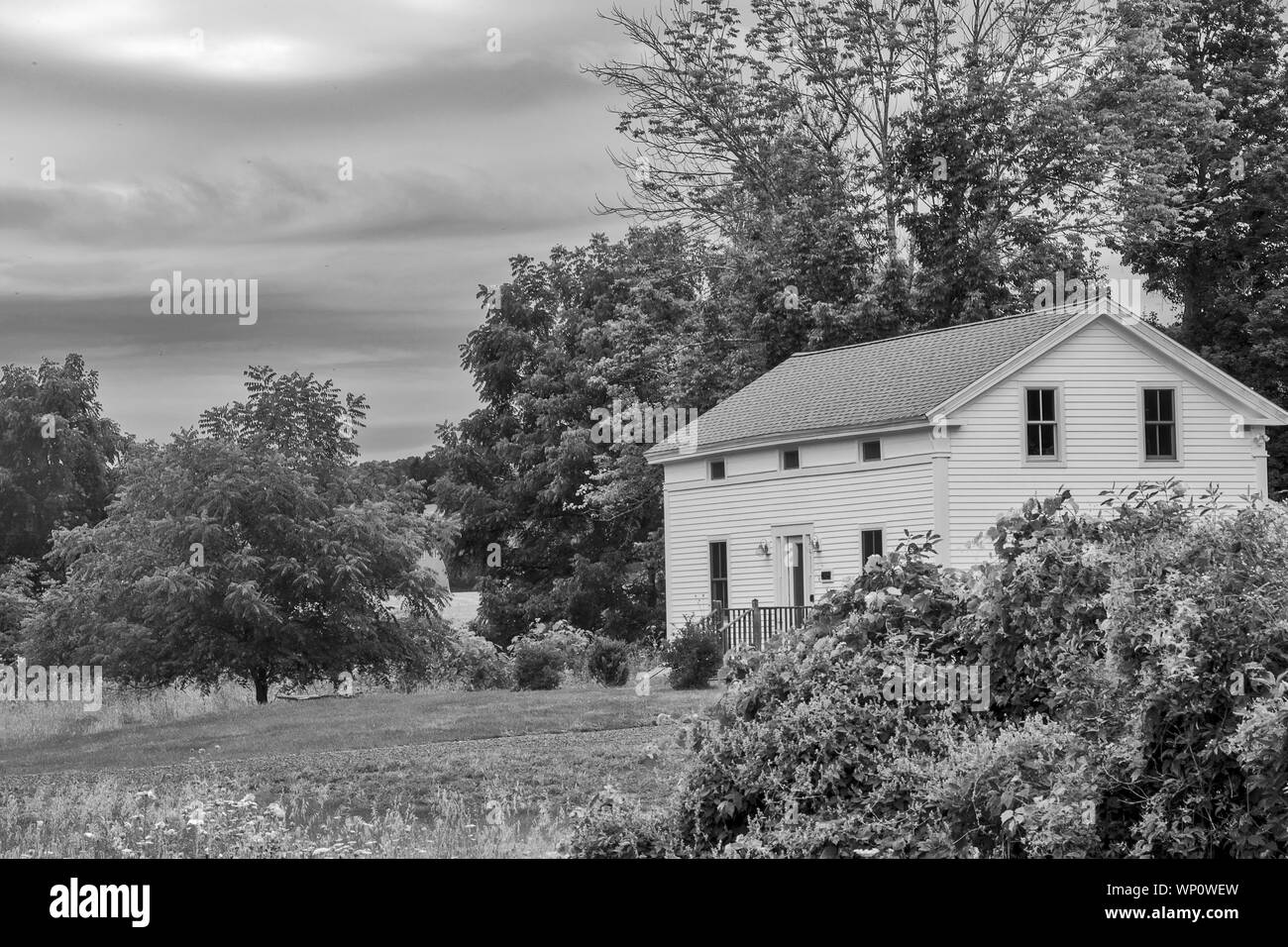 Un clapboard casa di campagna con cielo tempestoso in background. Foto Stock