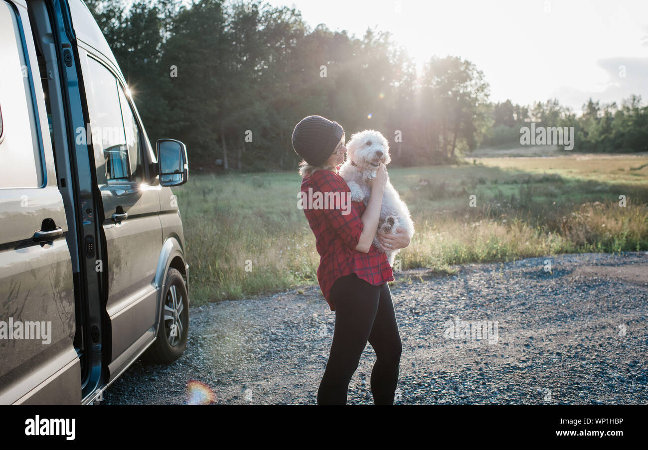 Donna che mantiene il suo cane mentre campeggio in un camper in estate Foto Stock