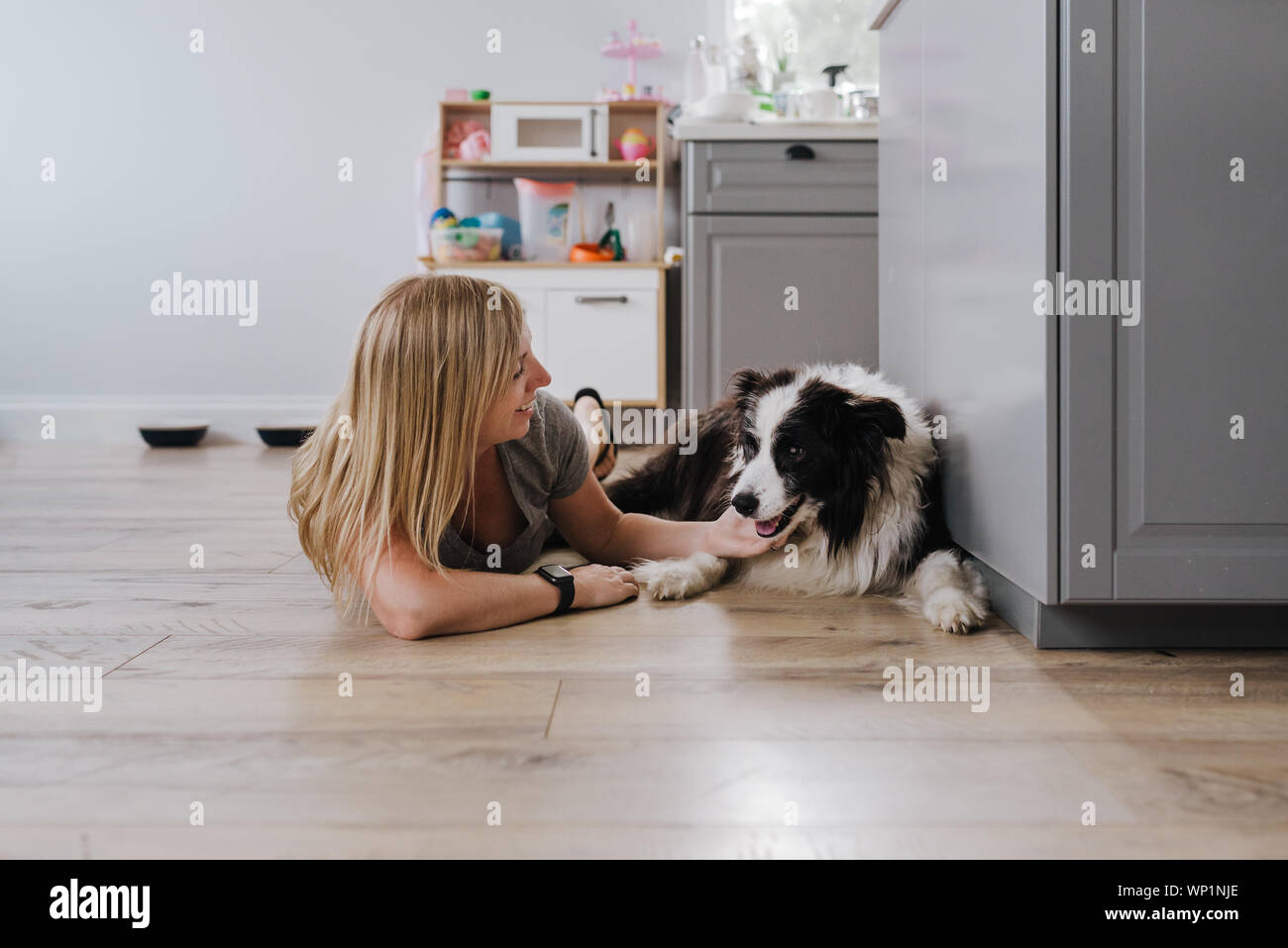 Felice donna sorridente mentre petting il suo cane a casa Foto Stock