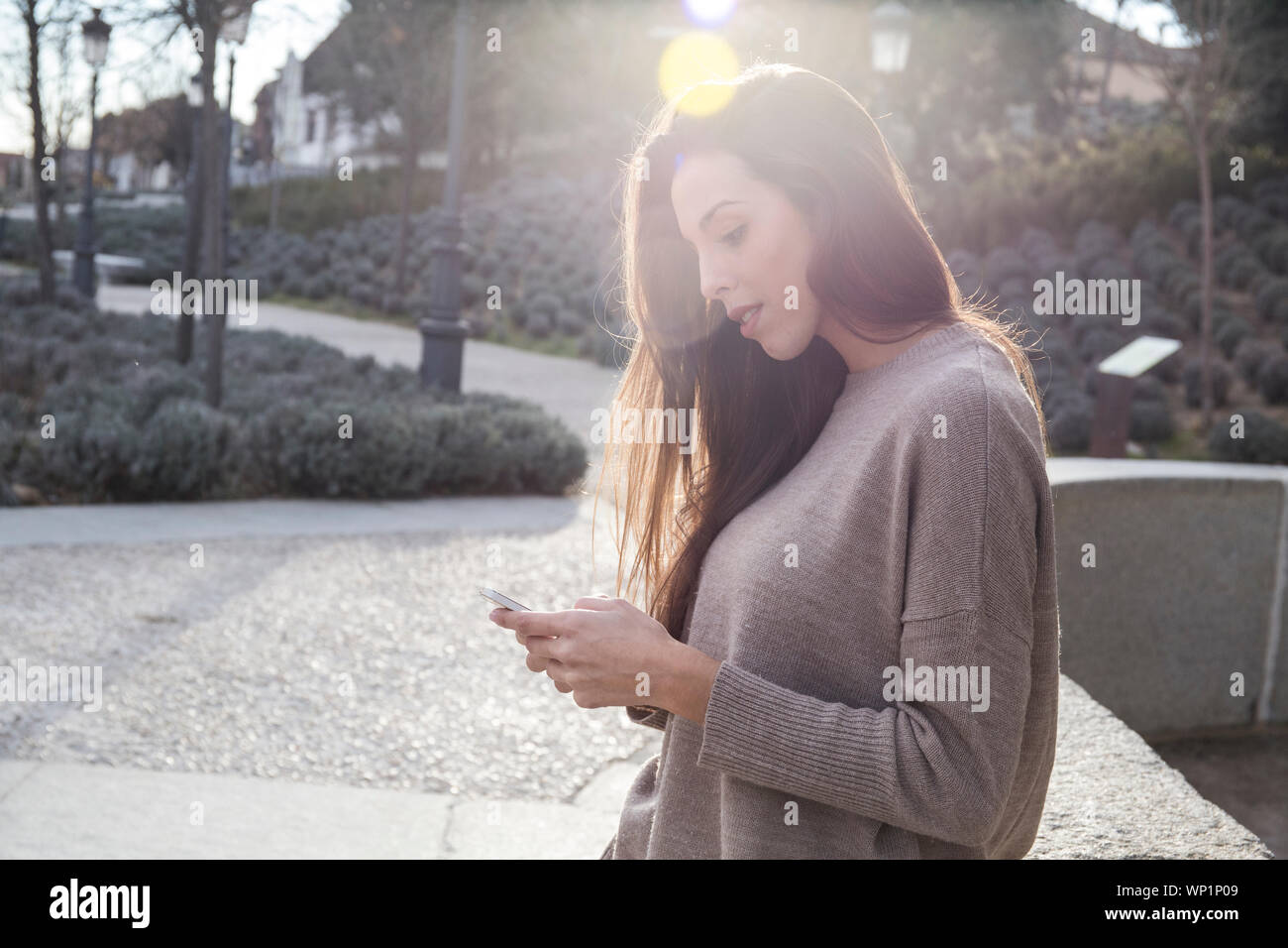 Donna che usa il suo smartphone mentre in piedi vicino alla strada di Boadilla Foto Stock