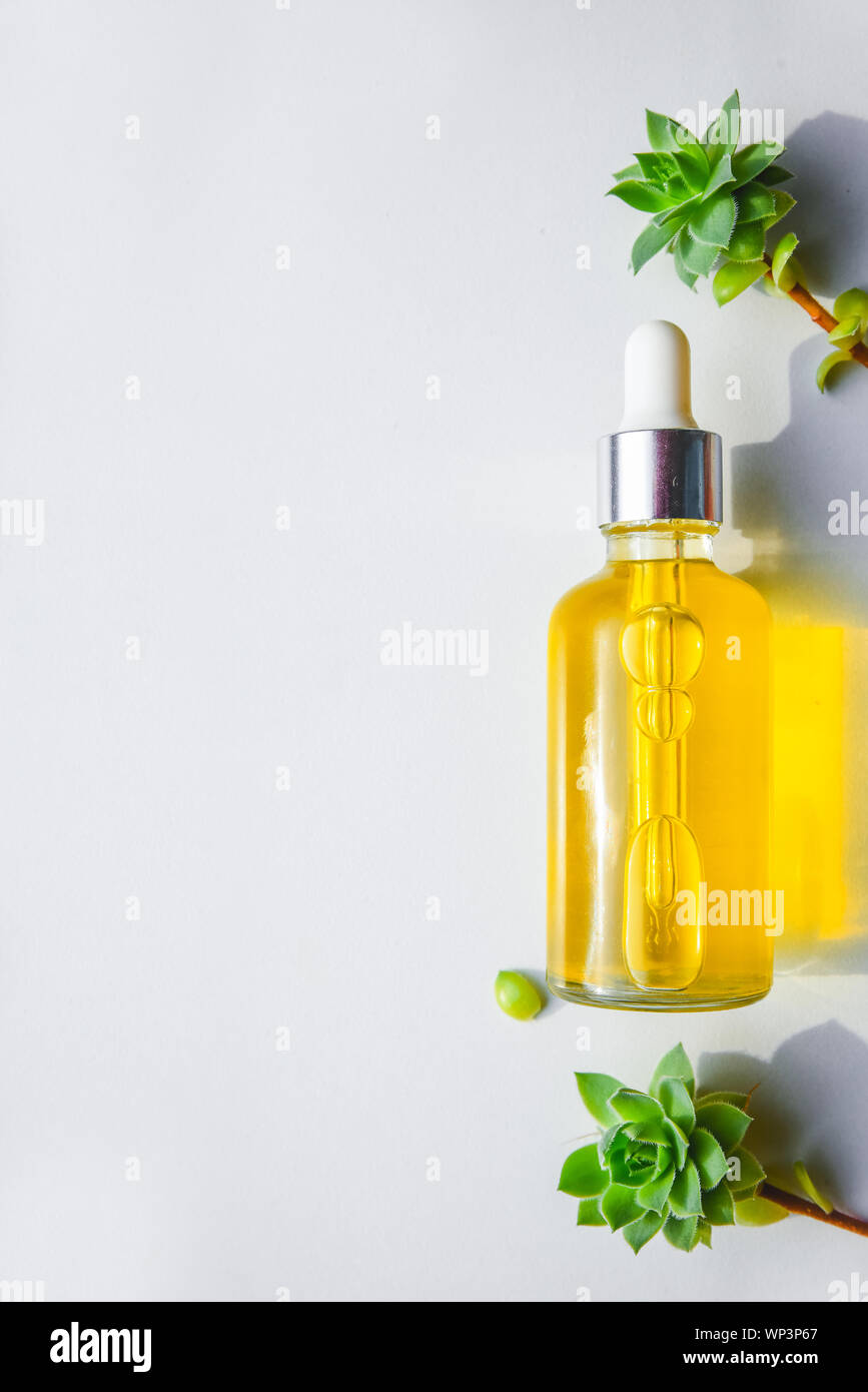 Siero con vitamina C naturale, olio cosmetico in una bottiglia di vetro con una pipetta. Sfondo Llight Foto Stock