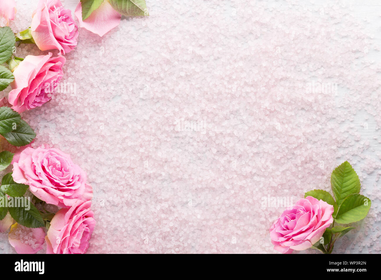 Spa i cristalli di sale e le rose rosa con foglie verdi. Lay piatto. Foto Stock