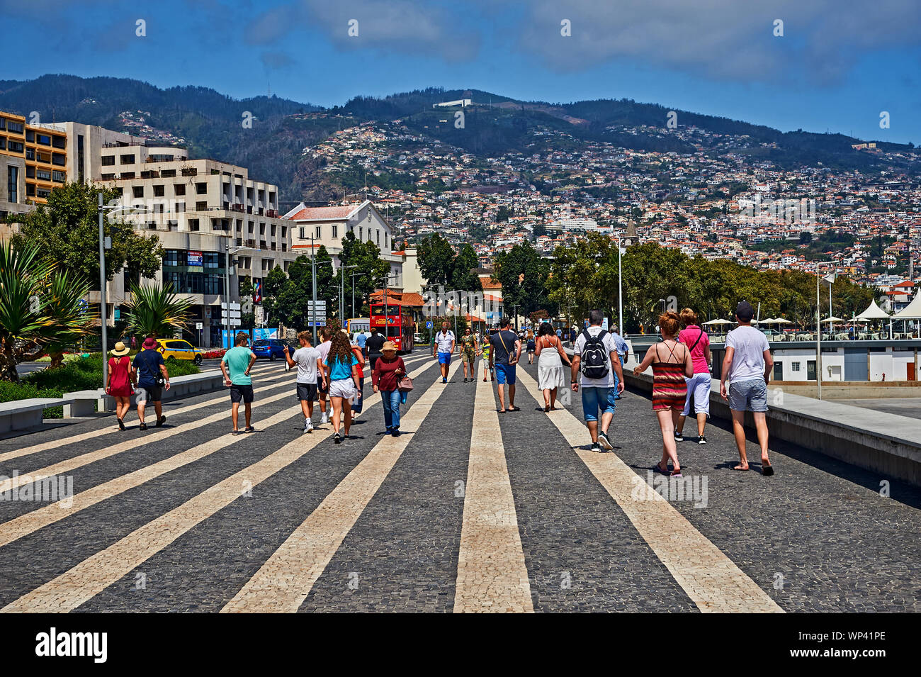 Funchal, Madeira i turisti e i locali a piedi lungo la strada pedonale Quayside. Il pattern nella footway crea le linee convergenti. Foto Stock