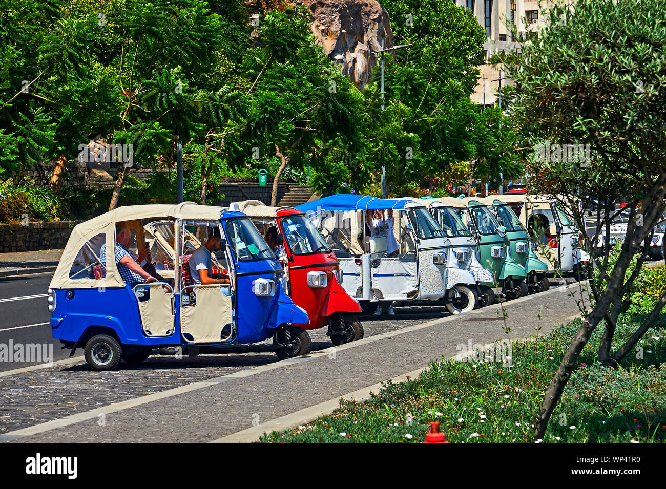 Funchal, Madeira e colorato tuk tuks sono allineati al lato della strada in attesa di locazione da turisti e visitatori della città. Foto Stock